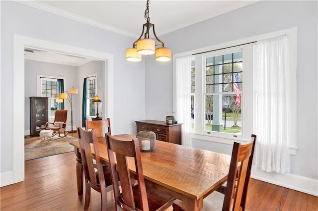 dining space with ornamental molding, baseboards, and wood finished floors