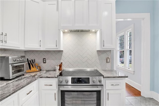 kitchen featuring stainless steel electric range, white cabinets, and backsplash