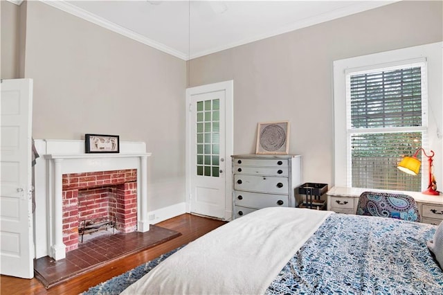 bedroom with a fireplace, crown molding, baseboards, and wood finished floors