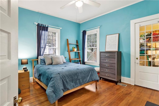 bedroom featuring visible vents, baseboards, a ceiling fan, hardwood / wood-style floors, and crown molding