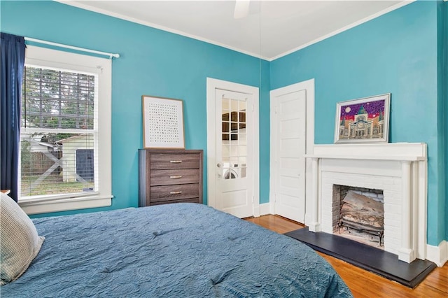 bedroom featuring crown molding, a fireplace, baseboards, and wood finished floors