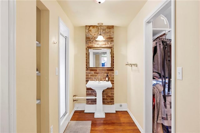 full bath with a sink, a stall shower, wood finished floors, and baseboards