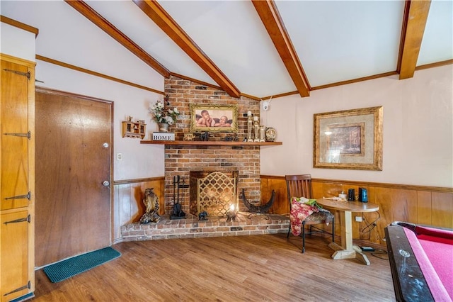 living room with wood-type flooring, wooden walls, a brick fireplace, and vaulted ceiling with beams