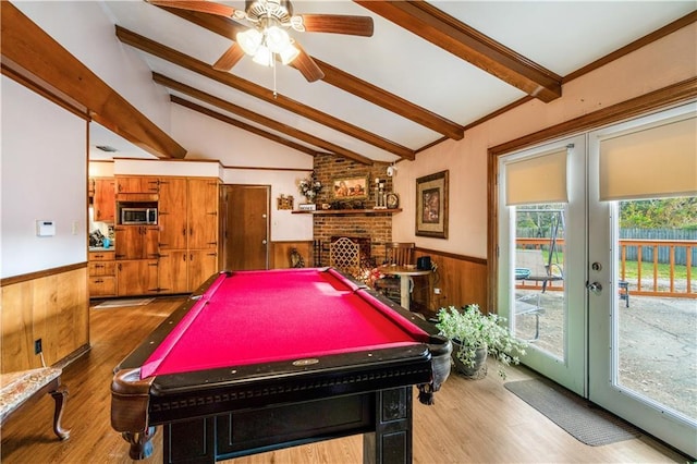 rec room featuring wood-type flooring, vaulted ceiling with beams, a fireplace, and wood walls