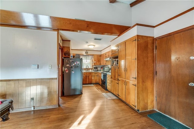 kitchen featuring appliances with stainless steel finishes, sink, beam ceiling, and light hardwood / wood-style flooring