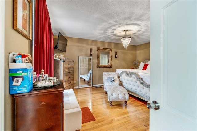 bedroom featuring a chandelier, a textured ceiling, and light wood-type flooring