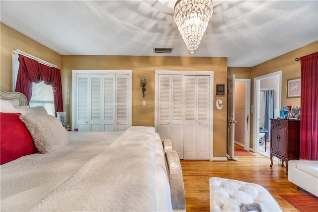 bedroom featuring multiple closets, wood-type flooring, and a notable chandelier