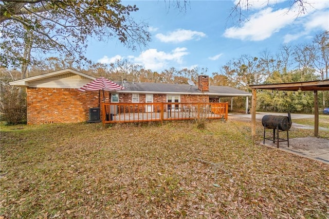 rear view of house featuring a wooden deck, a carport, a yard, and central AC