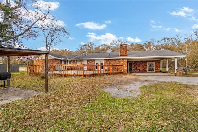 rear view of house featuring a carport, a deck, and a lawn