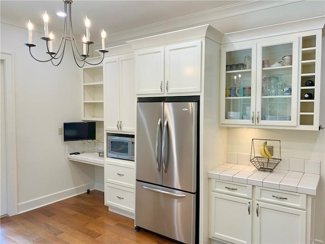 kitchen with white cabinets, an inviting chandelier, decorative light fixtures, stainless steel appliances, and wood-type flooring