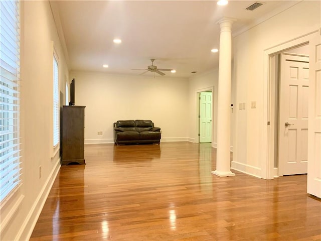 living room featuring plenty of natural light, wood-type flooring, and ornate columns