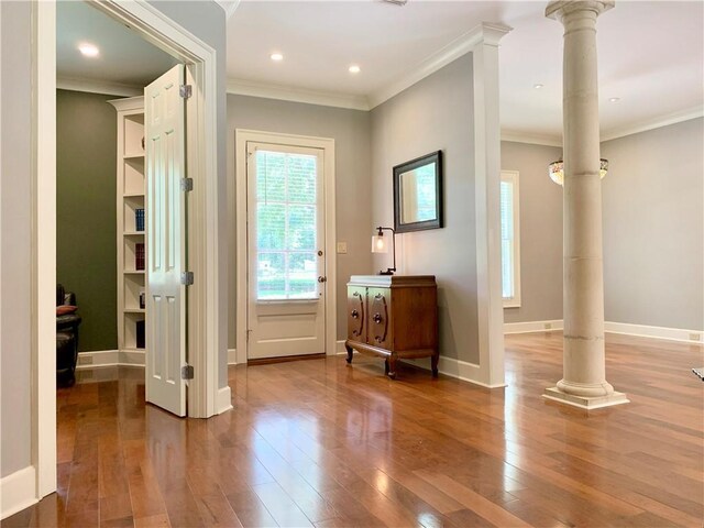 entryway featuring hardwood / wood-style flooring, crown molding, and ornate columns