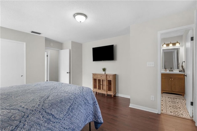 bedroom featuring dark wood-style floors, visible vents, baseboards, and a sink