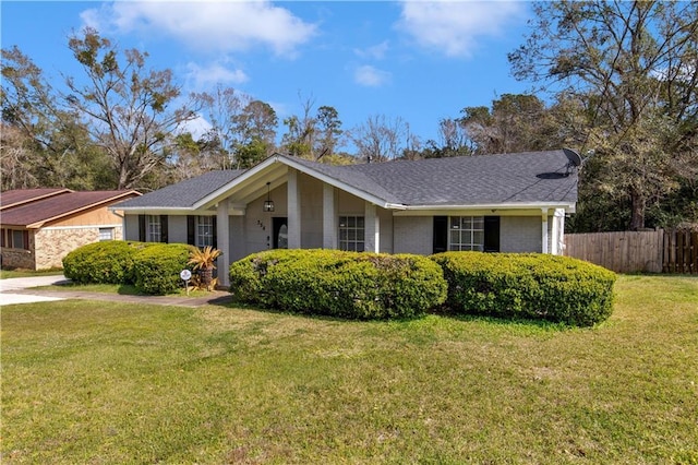 view of front of property with a front lawn, fence, brick siding, and roof with shingles