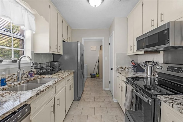 kitchen with backsplash, white cabinets, stainless steel appliances, and a sink