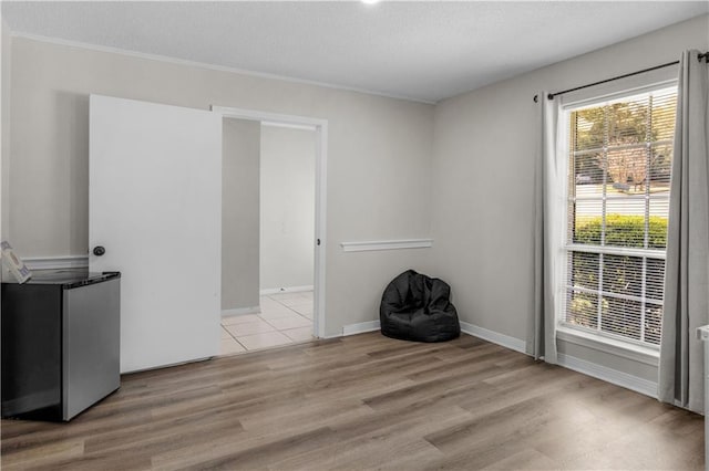 unfurnished room with light wood-type flooring, plenty of natural light, and a textured ceiling