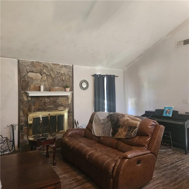 living room with a stone fireplace, vaulted ceiling, wood finished floors, and visible vents