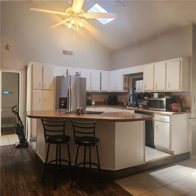 kitchen featuring visible vents, appliances with stainless steel finishes, a center island, and white cabinetry