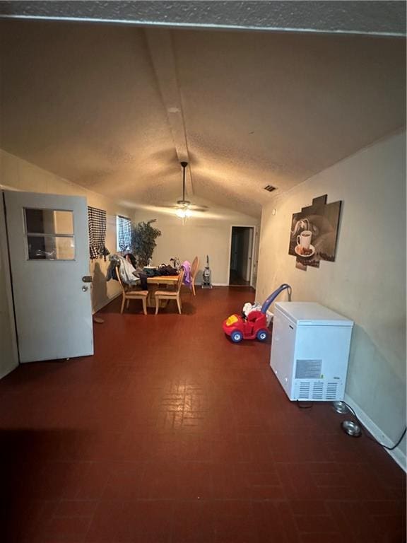 rec room featuring ceiling fan, vaulted ceiling, and a textured ceiling