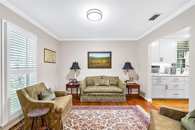 living room with sink, ornamental molding, and hardwood / wood-style floors