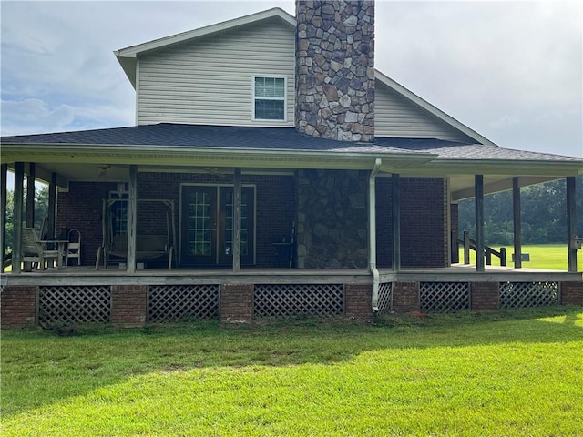 rear view of house featuring a yard and covered porch