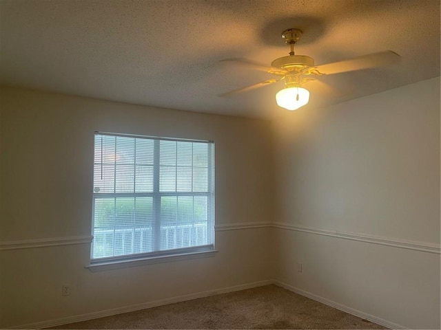 empty room featuring ceiling fan, a textured ceiling, and carpet