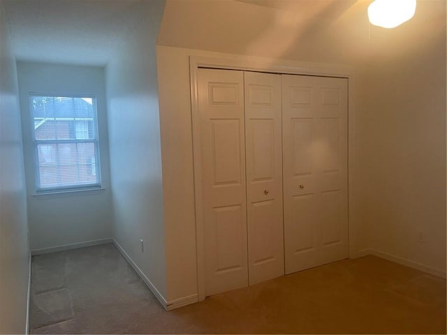 unfurnished bedroom featuring light colored carpet and a closet