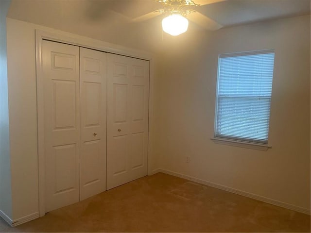 unfurnished bedroom featuring a closet, light colored carpet, and ceiling fan