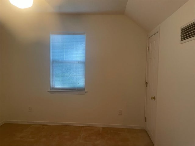 carpeted spare room featuring vaulted ceiling