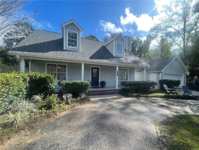 cape cod home featuring a garage and a porch