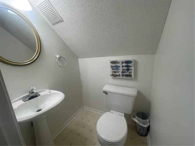 bathroom with toilet, vaulted ceiling, and a textured ceiling