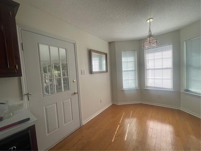 unfurnished dining area featuring light hardwood / wood-style floors and a textured ceiling