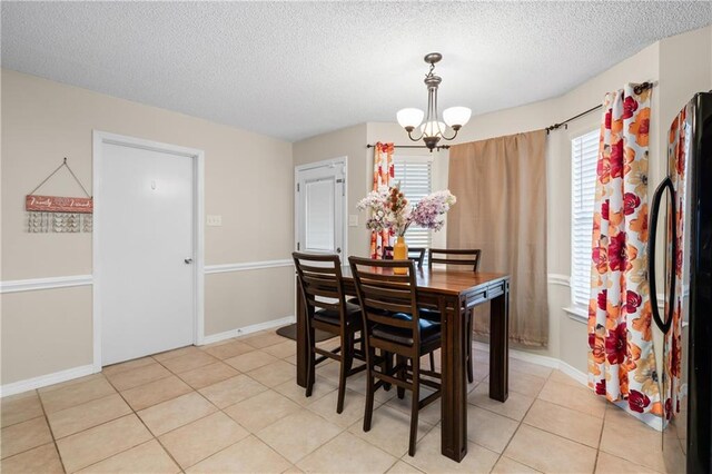 tiled dining area featuring a textured ceiling, a chandelier, and a healthy amount of sunlight