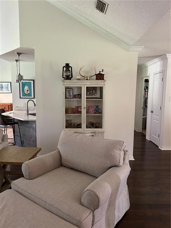 living room featuring ornamental molding, lofted ceiling, a textured ceiling, and dark hardwood / wood-style flooring