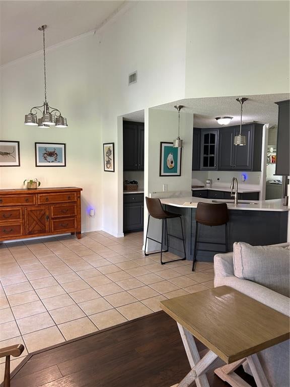 living room featuring a notable chandelier, light wood-type flooring, sink, and high vaulted ceiling