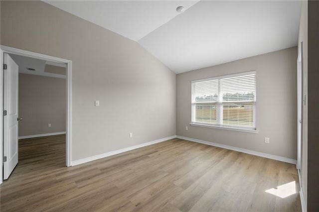 spare room featuring lofted ceiling and light hardwood / wood-style floors