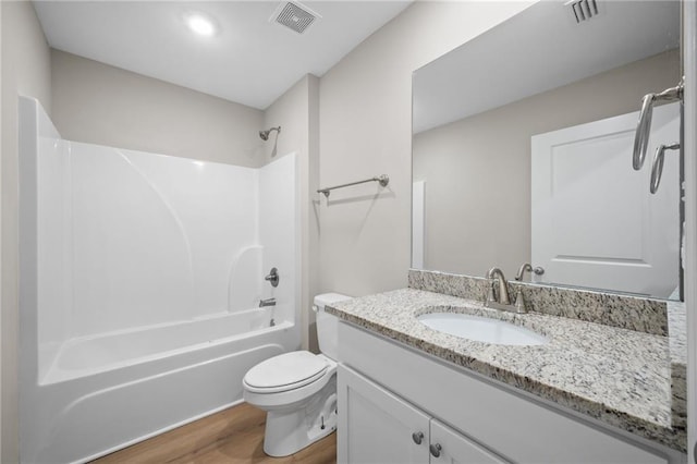 full bathroom with hardwood / wood-style flooring, washtub / shower combination, vanity, and toilet