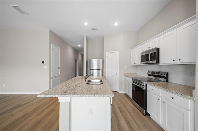 kitchen with stainless steel appliances, an island with sink, sink, and white cabinets