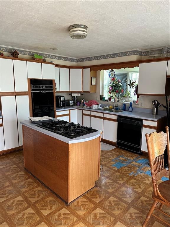 kitchen with parquet floors, white cabinetry, sink, a textured ceiling, and black appliances