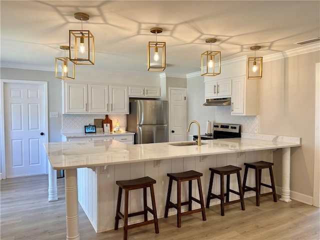 kitchen with under cabinet range hood, stainless steel appliances, a peninsula, a sink, and visible vents