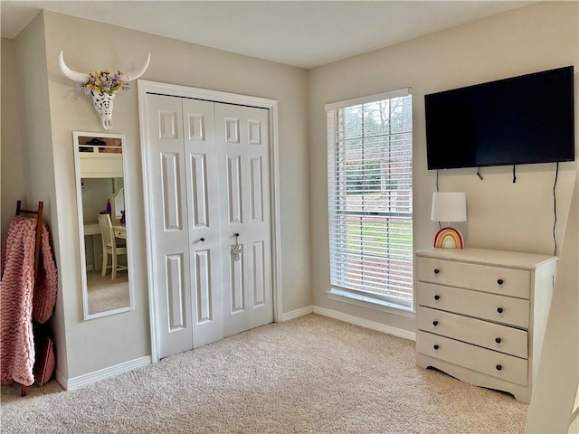 bedroom with light carpet, baseboards, and a closet