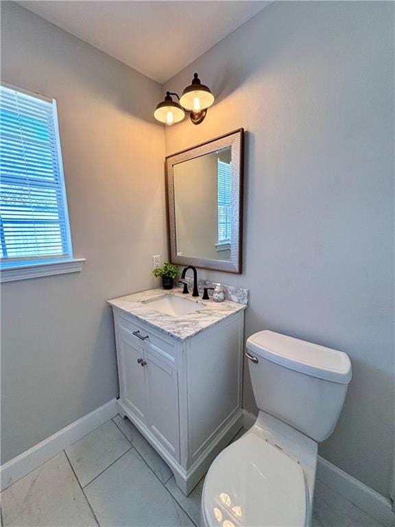 bathroom featuring baseboards, vanity, and toilet