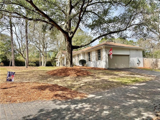 single story home with a garage, fence, aphalt driveway, and brick siding