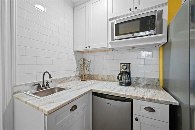3120 Riviere Du Chien Loop W, Mobile, AL 36693 - kitchen featuring appliances with stainless steel finishes, backsplash, white cabinetry, and light stone counters