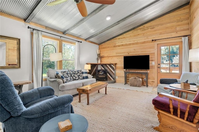 living room featuring a wealth of natural light, wood walls, ceiling fan, and high vaulted ceiling