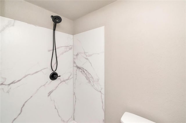 bathroom with tiled shower and toilet