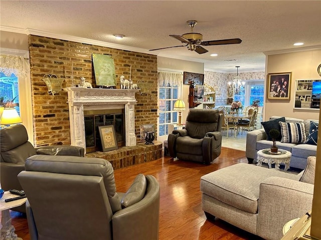 living room with a textured ceiling, a fireplace, ceiling fan with notable chandelier, and hardwood / wood-style flooring