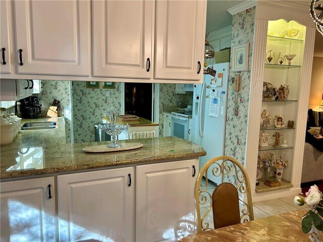 kitchen featuring stone counters, light tile patterned floors, white cabinets, and white appliances