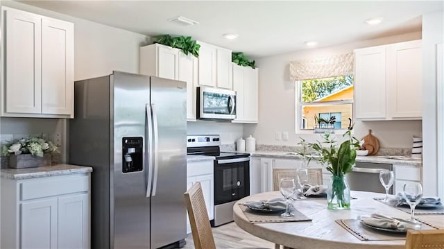 kitchen with white cabinets, light wood-type flooring, stainless steel appliances, and sink