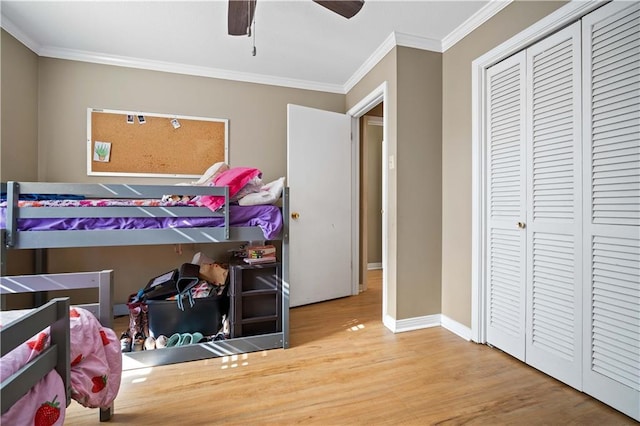 bedroom featuring hardwood / wood-style floors, a closet, ceiling fan, and crown molding